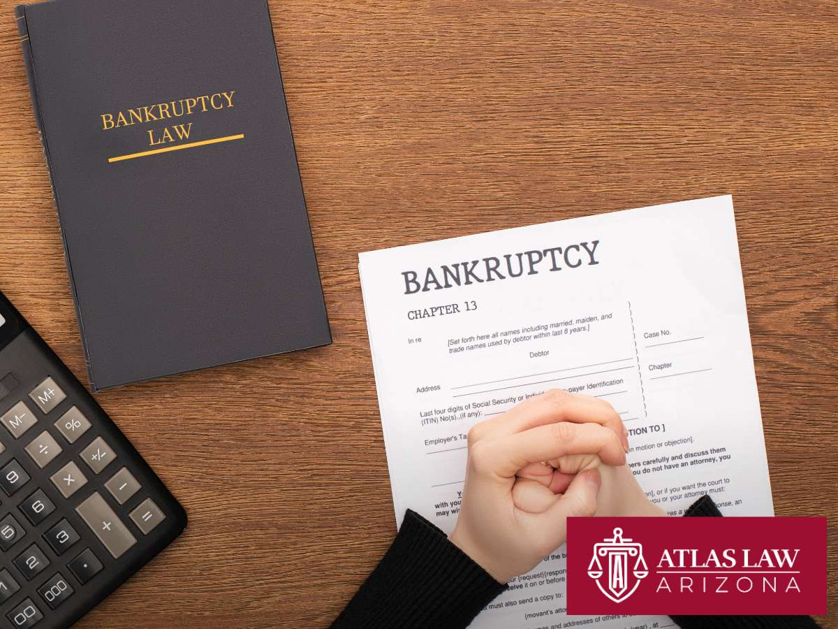 Person clasps hands over Chapter 13 Bankruptcy form beside a law book and calculator, highlighting legal and financial stress.